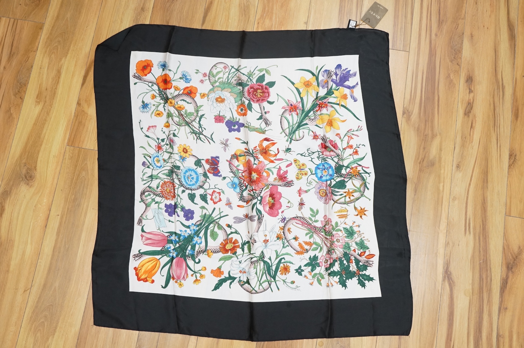 A Gucci floral silk scarf, with label and tag, a Gucci silk and net monogrammed scarf and a green & red monogrammed silk hair or bag ribbon